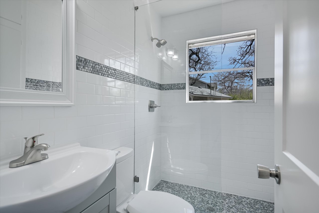 stunning new redesigned bathroom with unique glass partition, period subway tile walls and  stone accents